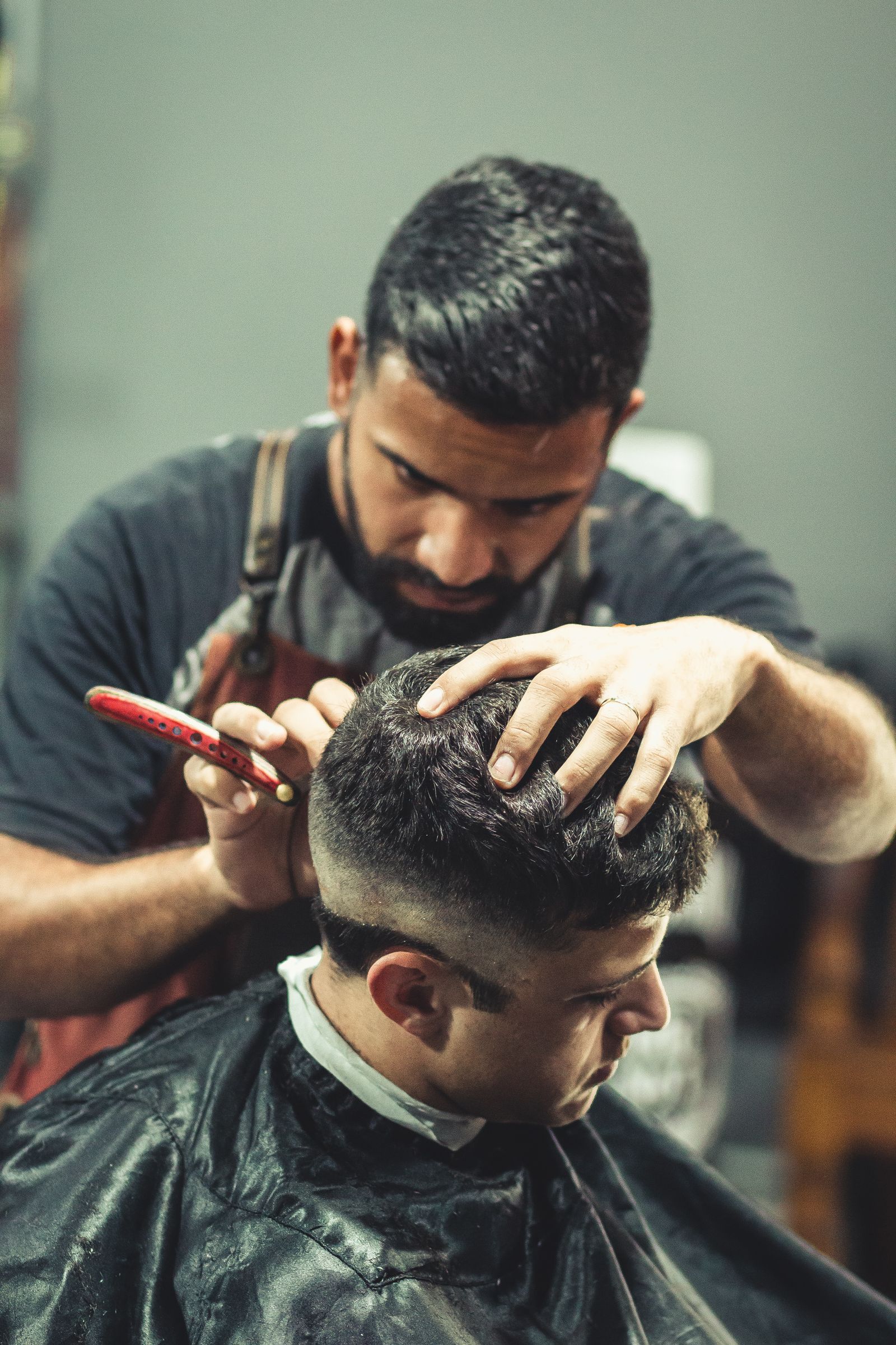 Barber holding clippers while cutting a seated client's hair.