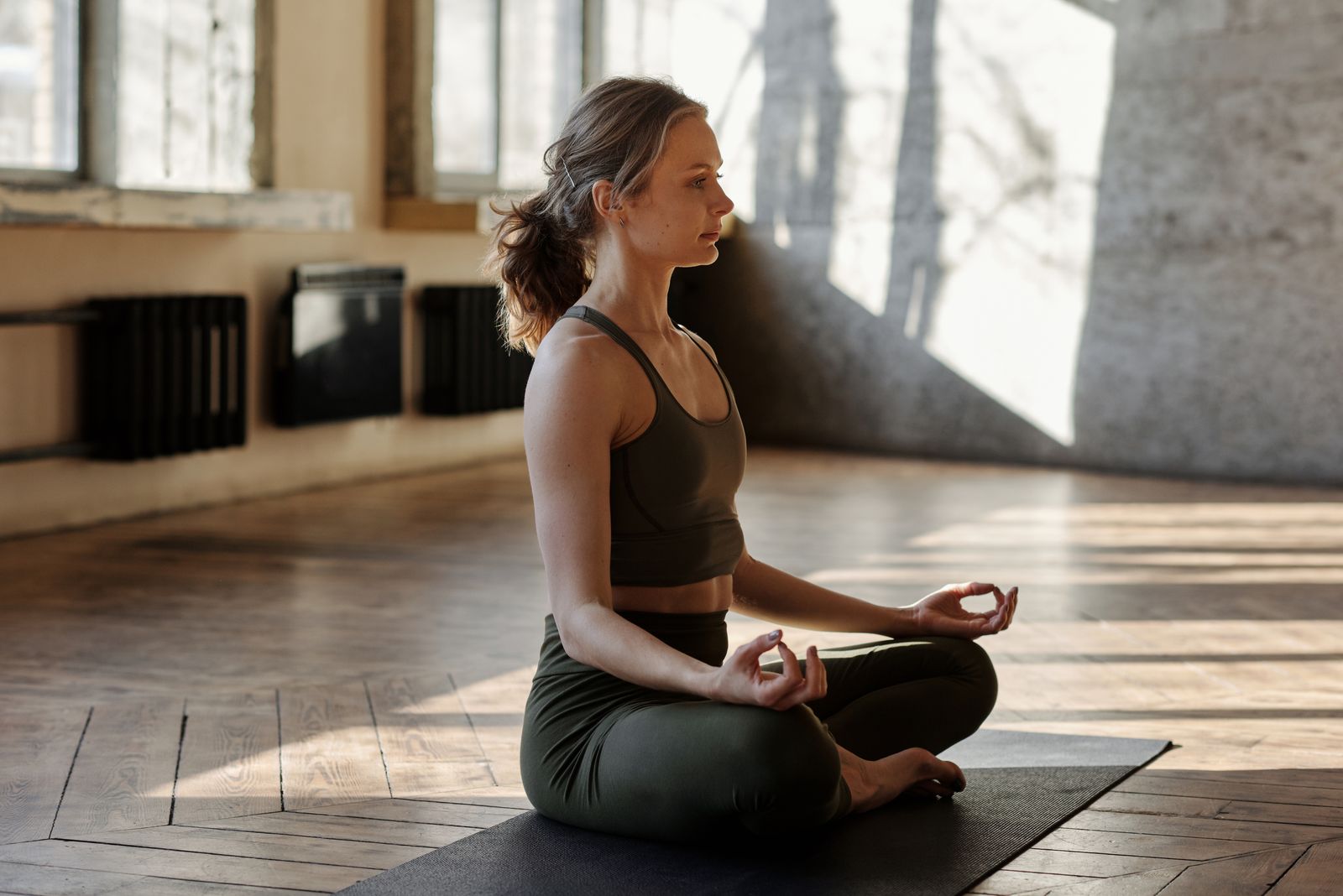 A woman meditating on a mat in a naturally lit studio