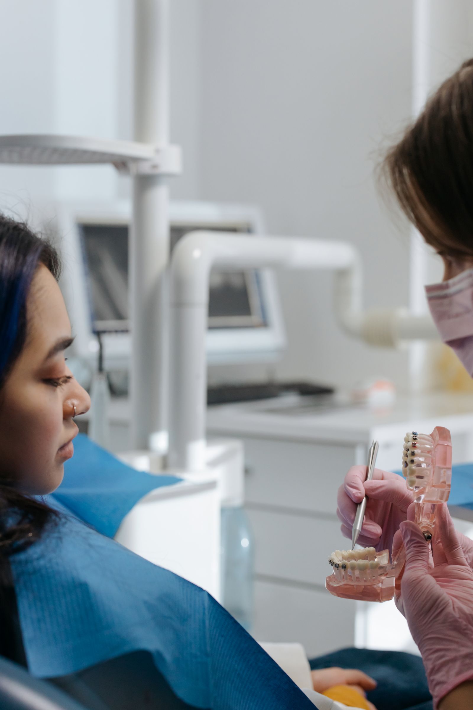 A dentist discussing a dental model with an adult patient.