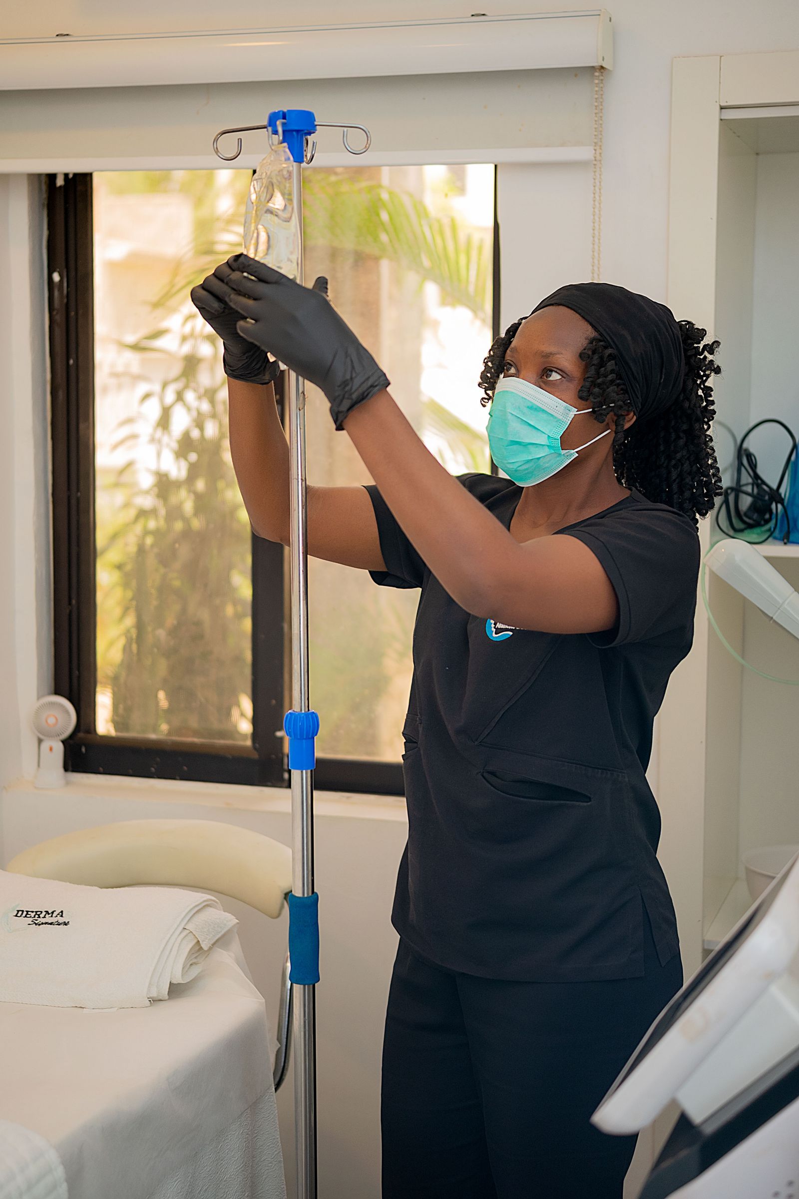 A healthcare professional adjusting an IV drip in a clinic.