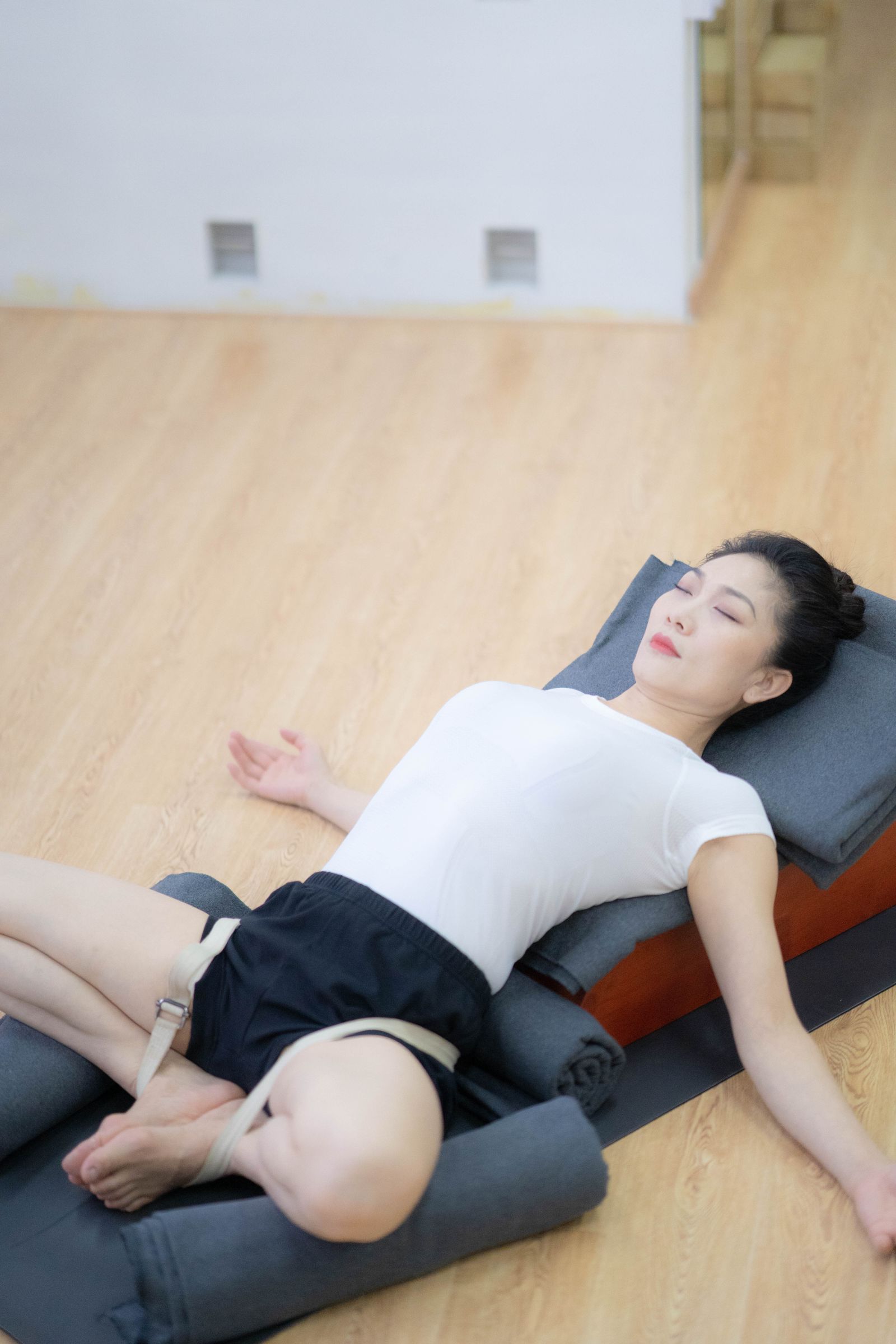 A woman resting on a bolster during a restorative yoga session.